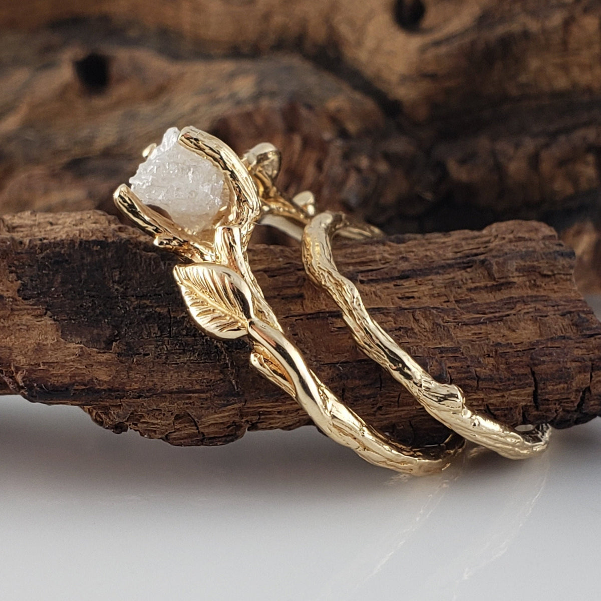 yellow gold twig and leaf style ring set with a white raw diamond