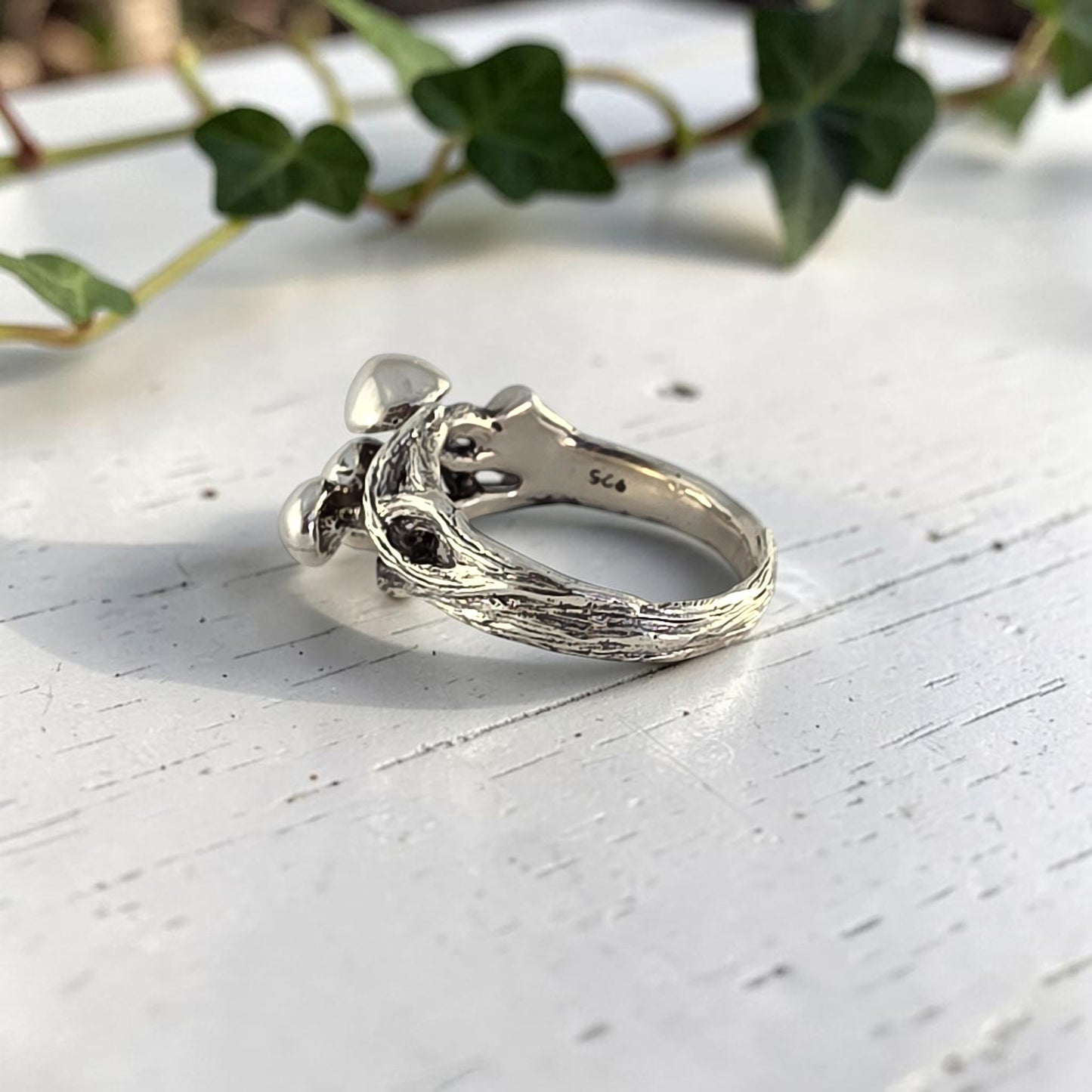 sterling silver ring with three mushrooms coming out of the top laying on its side to see inside the band