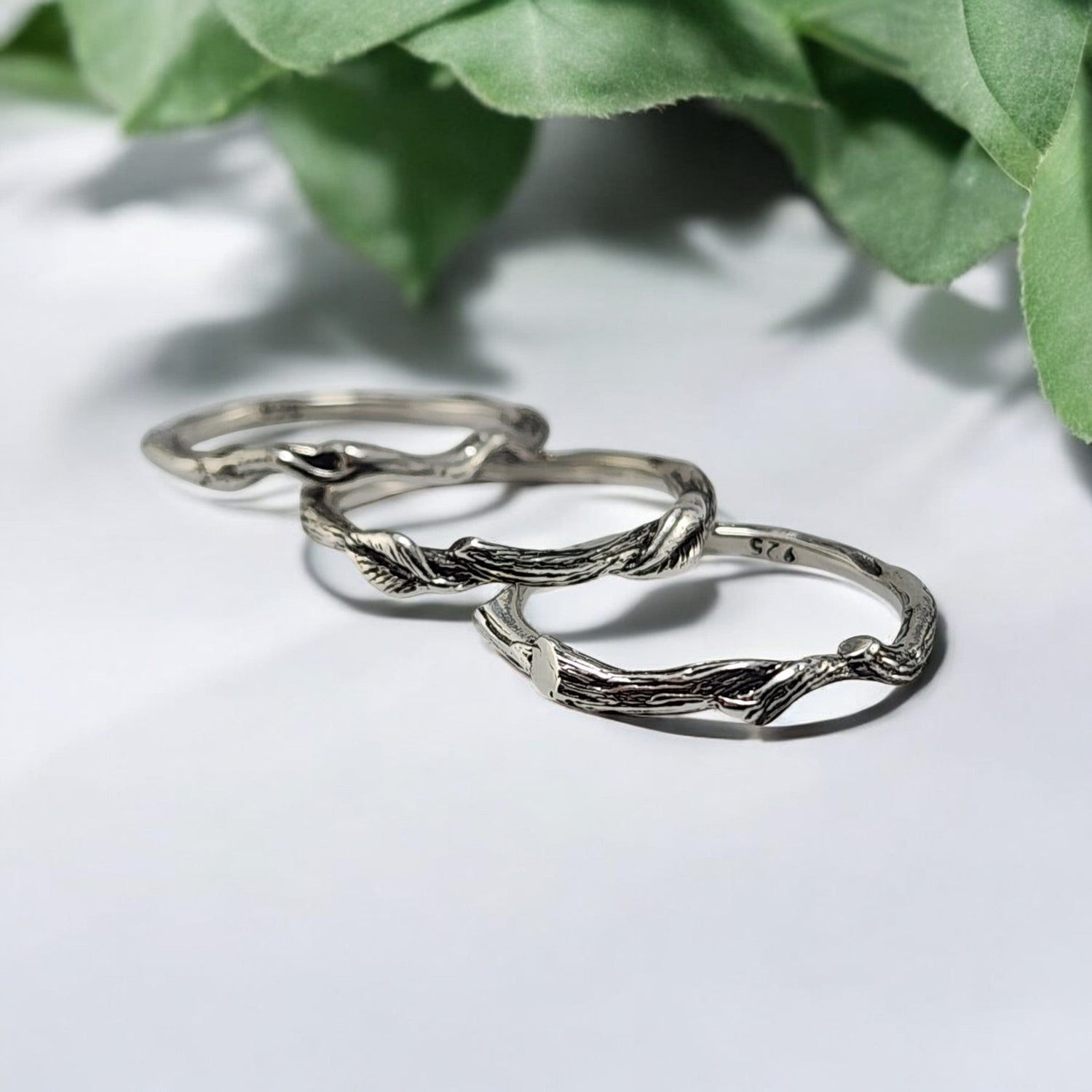 three silver nature themed rings laying on a table showing you how they stack together