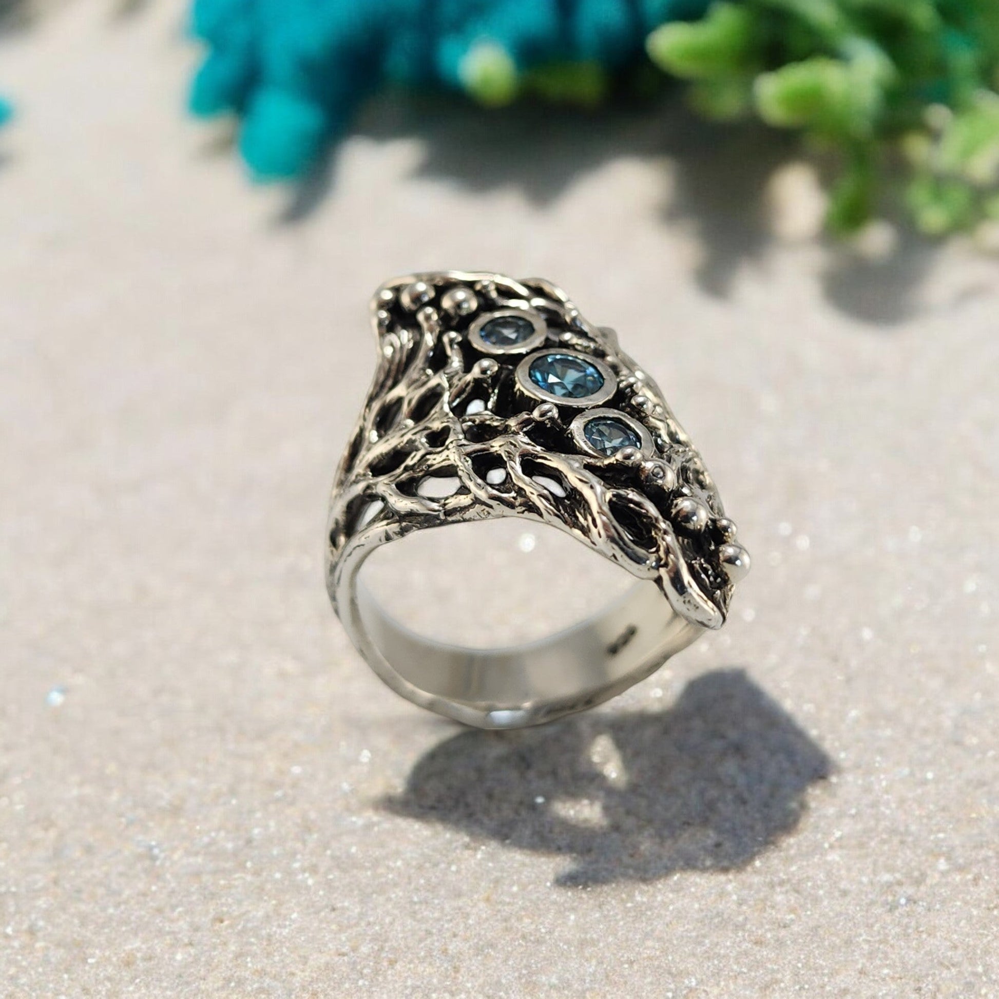 A silver ring with cricle blue gemstones down the center on the ring