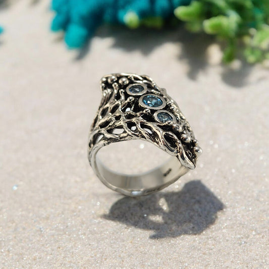 A silver ring with cricle blue gemstones down the center on the ring