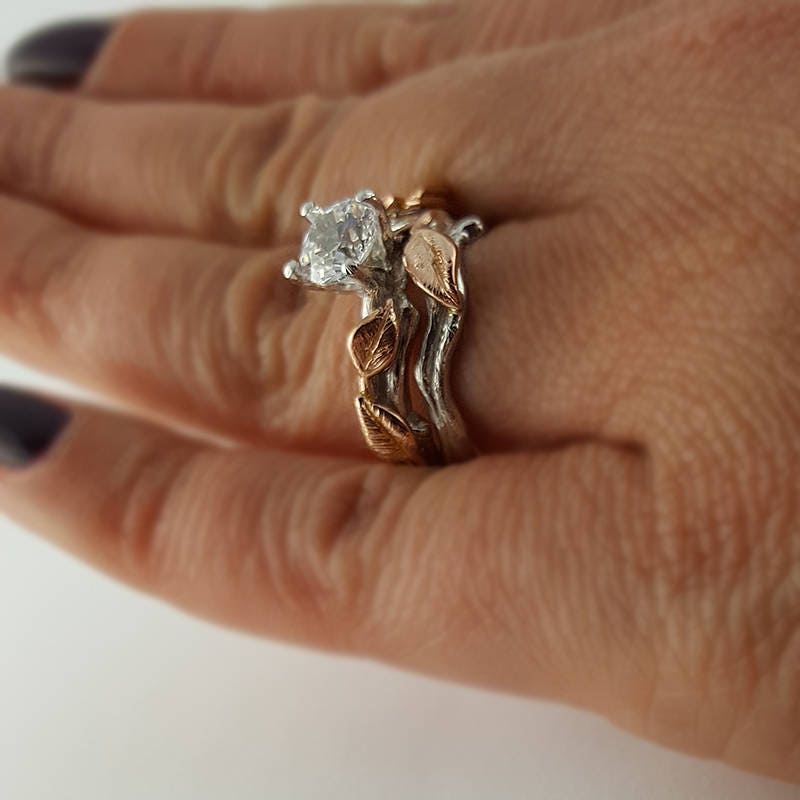 Rose gold ring with diamond on a hand against a white background
