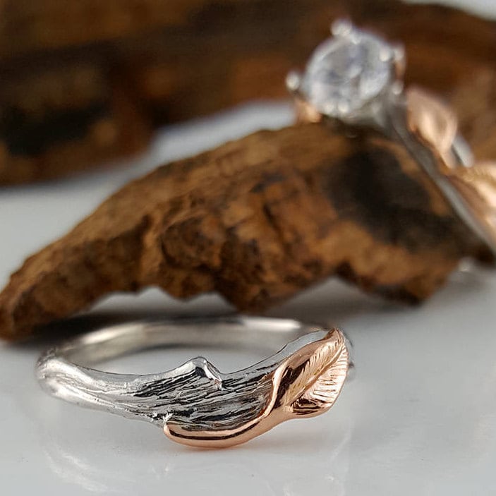 Two rings, one with a mountain design and the other with a diamond, on a textured surface.