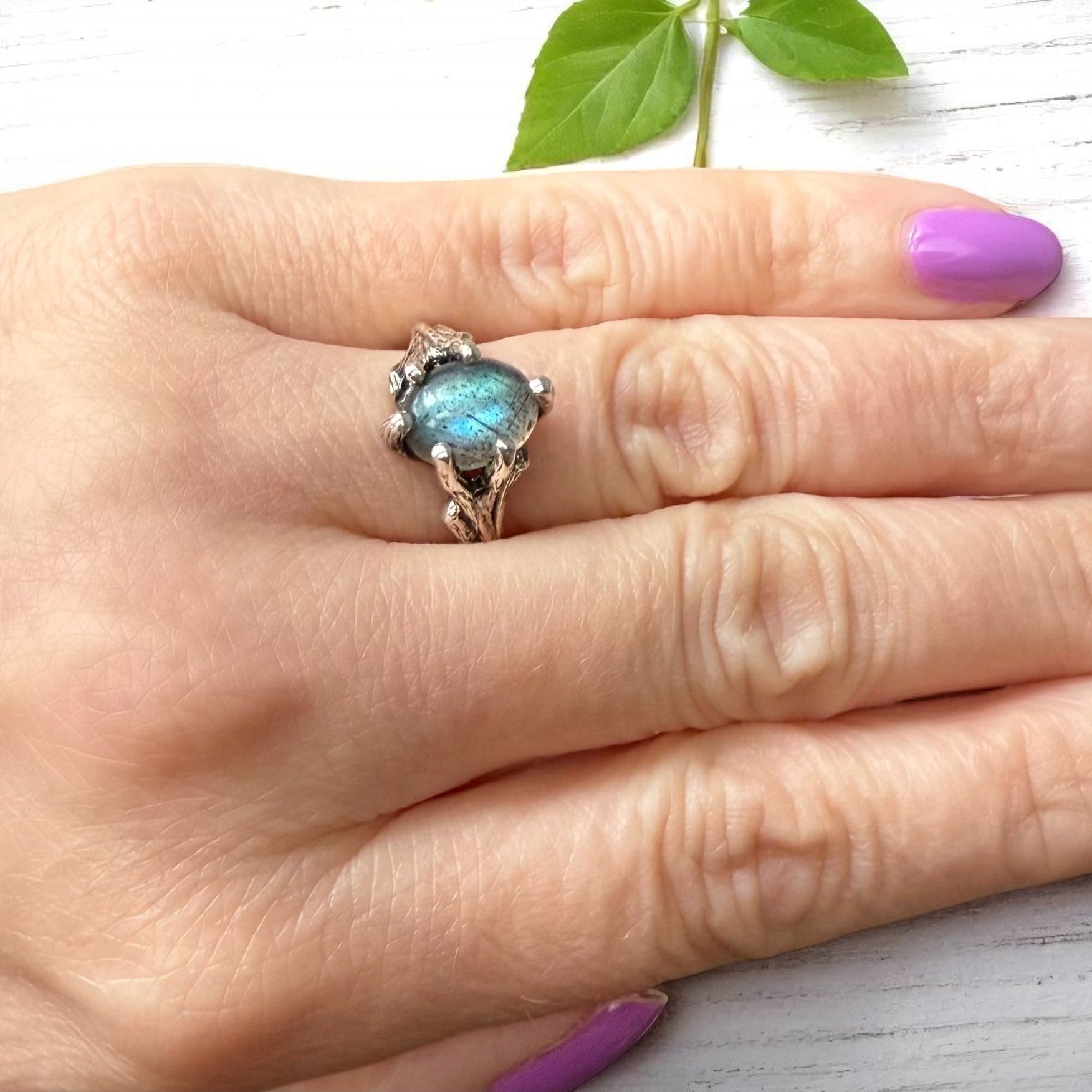 Labradorite sterling silver twig ring shown on a hand, nature-inspired solitaire with blue-green gemstone.
