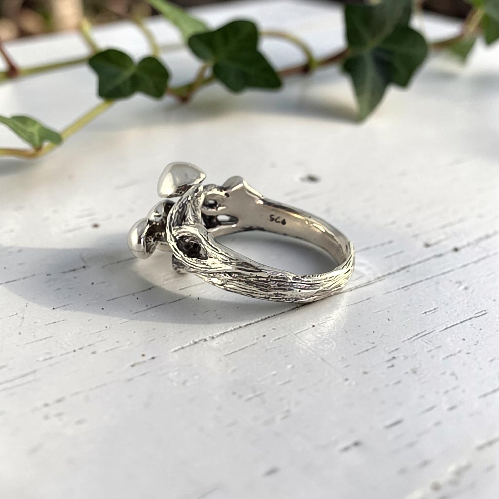 sterling silver ring with three mushrooms coming out of the top laying on its side to see inside the band