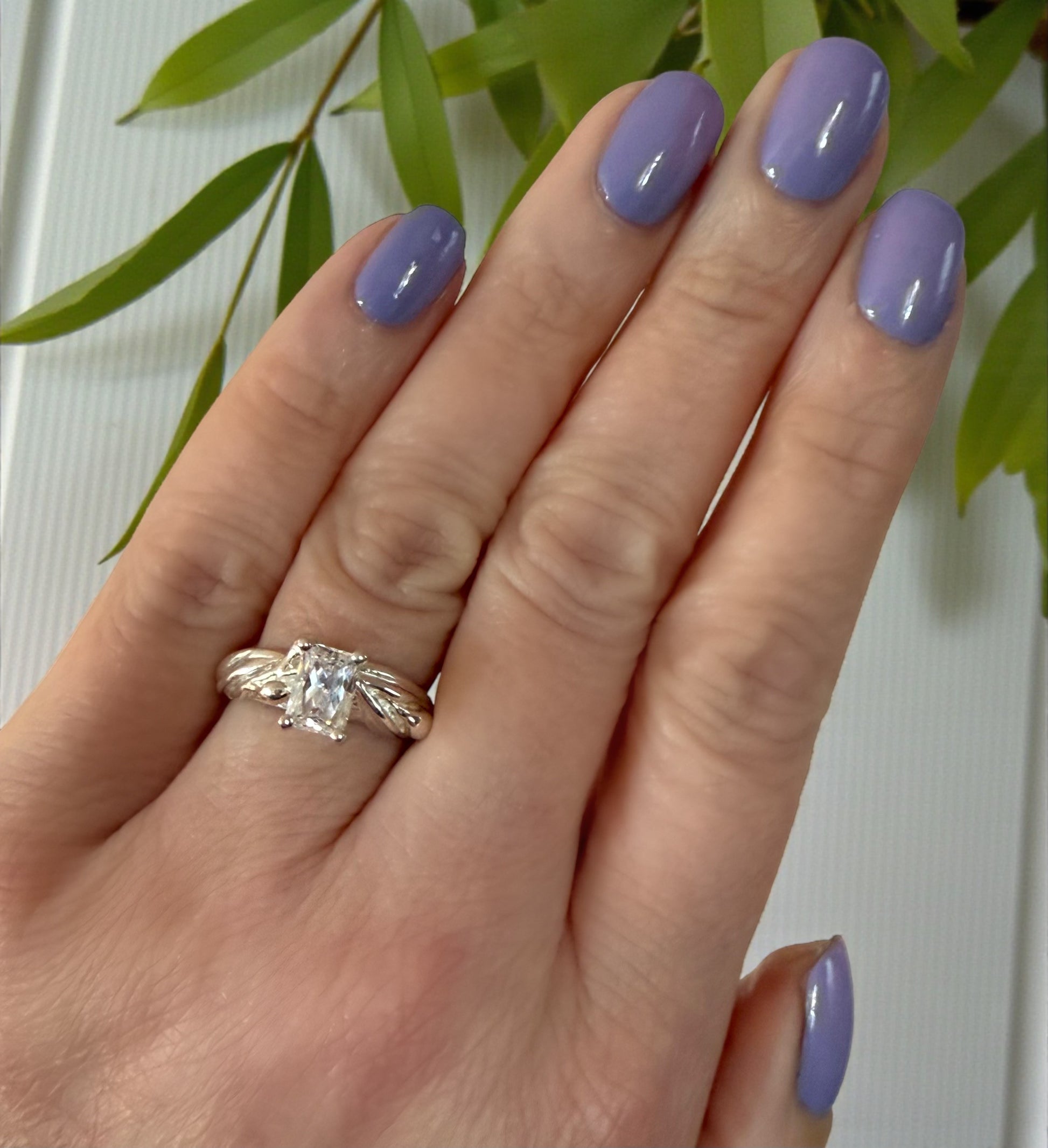 rectangle shaped moissanite diamond in white gold on a hand with a hand-sculpted olive leaves as the setting