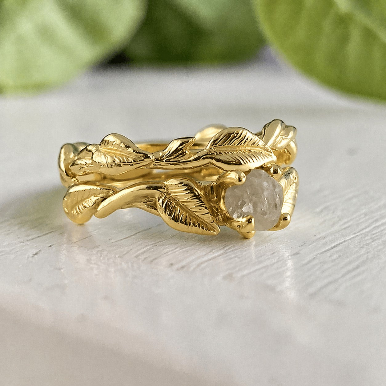 Gold ring with leaf design on a light surface