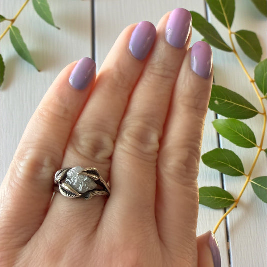 Raw diamond ring with leaves around the stone shown on a hand
