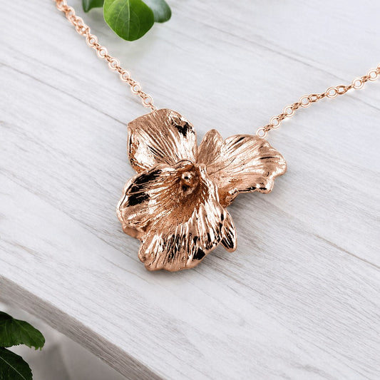Rose gold flower-shaped necklace on a light wooden surface
